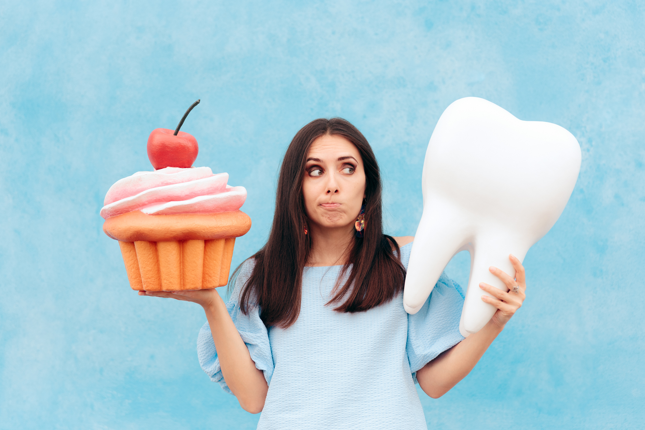 woman holding tooth and cupcake
